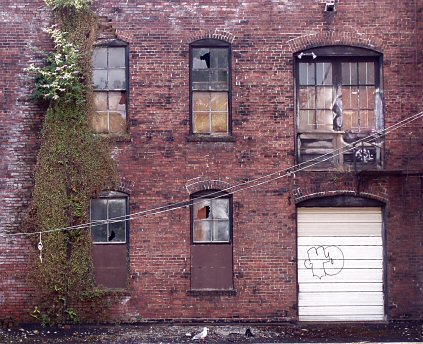 brick wall with six windows, some are broken