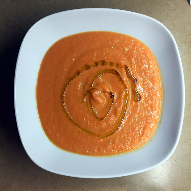 white bowl with orange soup and a drizzle of olive oil